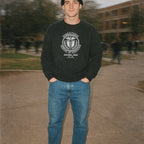 Man wearing Miskatonic School of Medicine sweatshirt with classic medical emblem and laurel wreath design outdoors