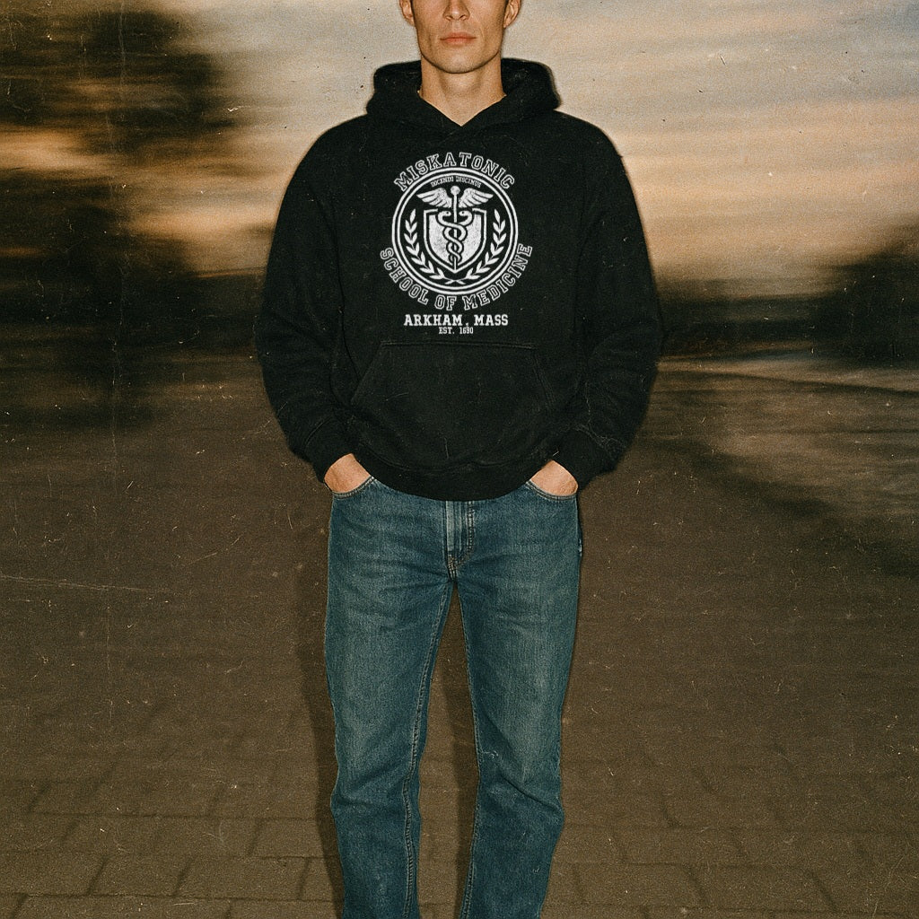 Person wearing a black hoodie with a logo and text, standing on a textured surface.