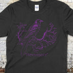 The Raven - "Nevermore" t-shirt featuring a purple raven perched on twisted branch line art on black fabric.