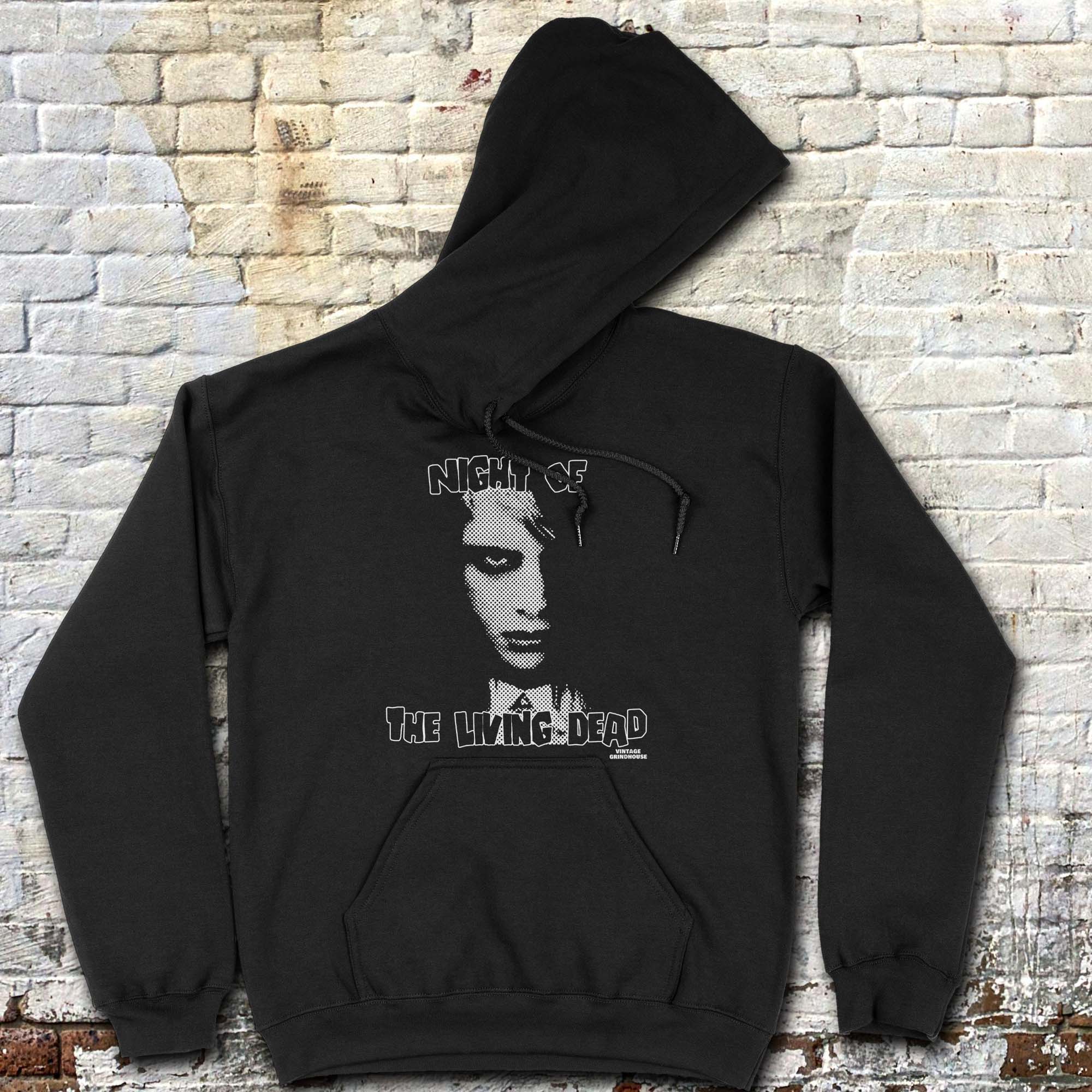 Night of the Living Dead hoodie featuring a black and white zombie face with distressed horror text on black fabric background