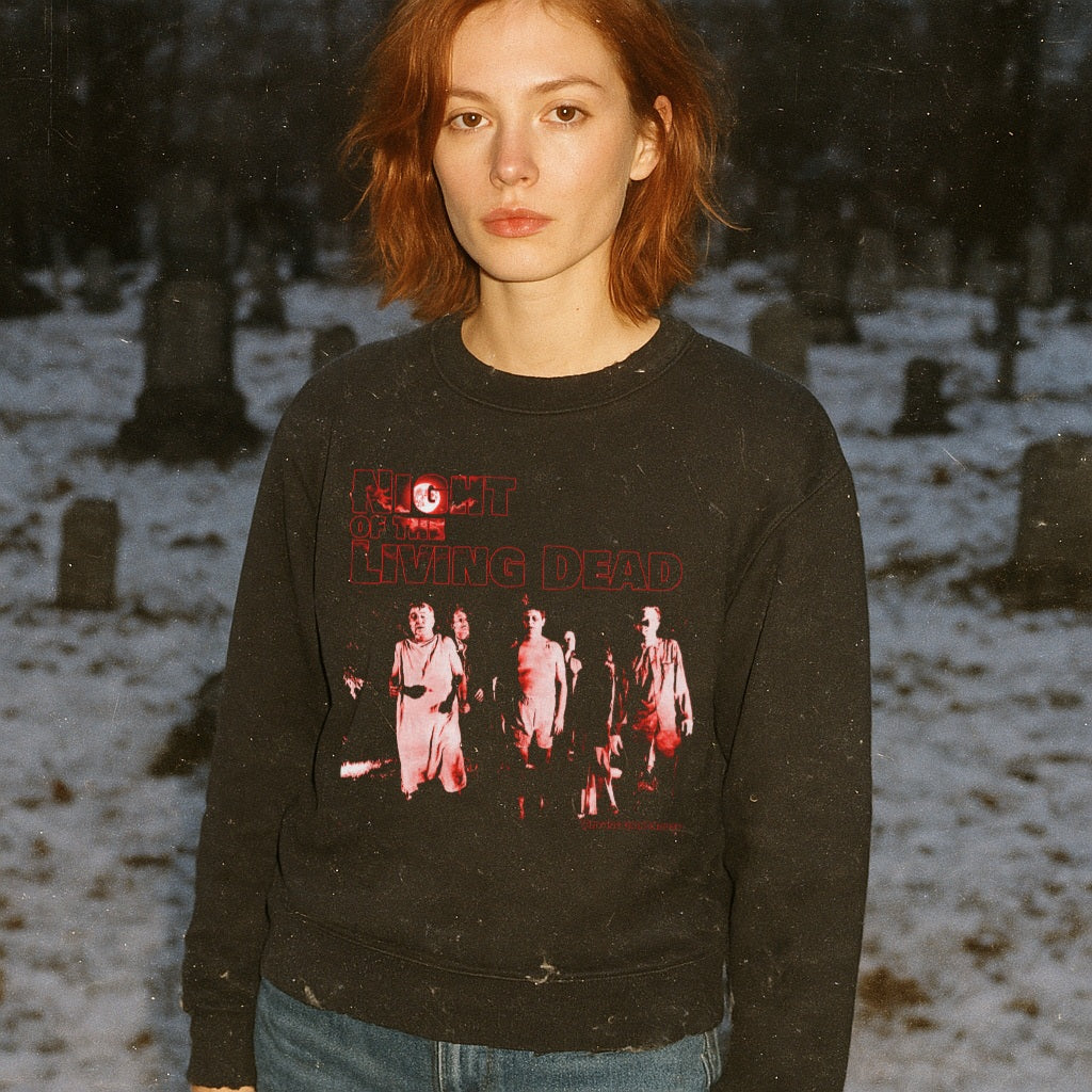 Night of the Living Dead sweatshirt with red graphic of undead figures and bold text on black fabric worn by woman outdoors