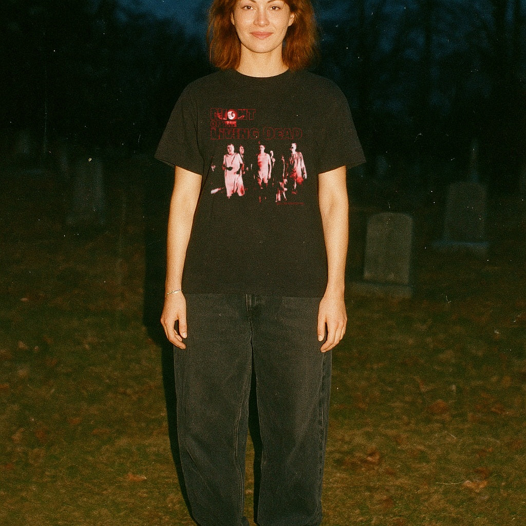 Person wearing a black t-shirt with a graphic design in a dark outdoor setting