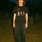 Person wearing a black t-shirt with a graphic design in a dark outdoor setting