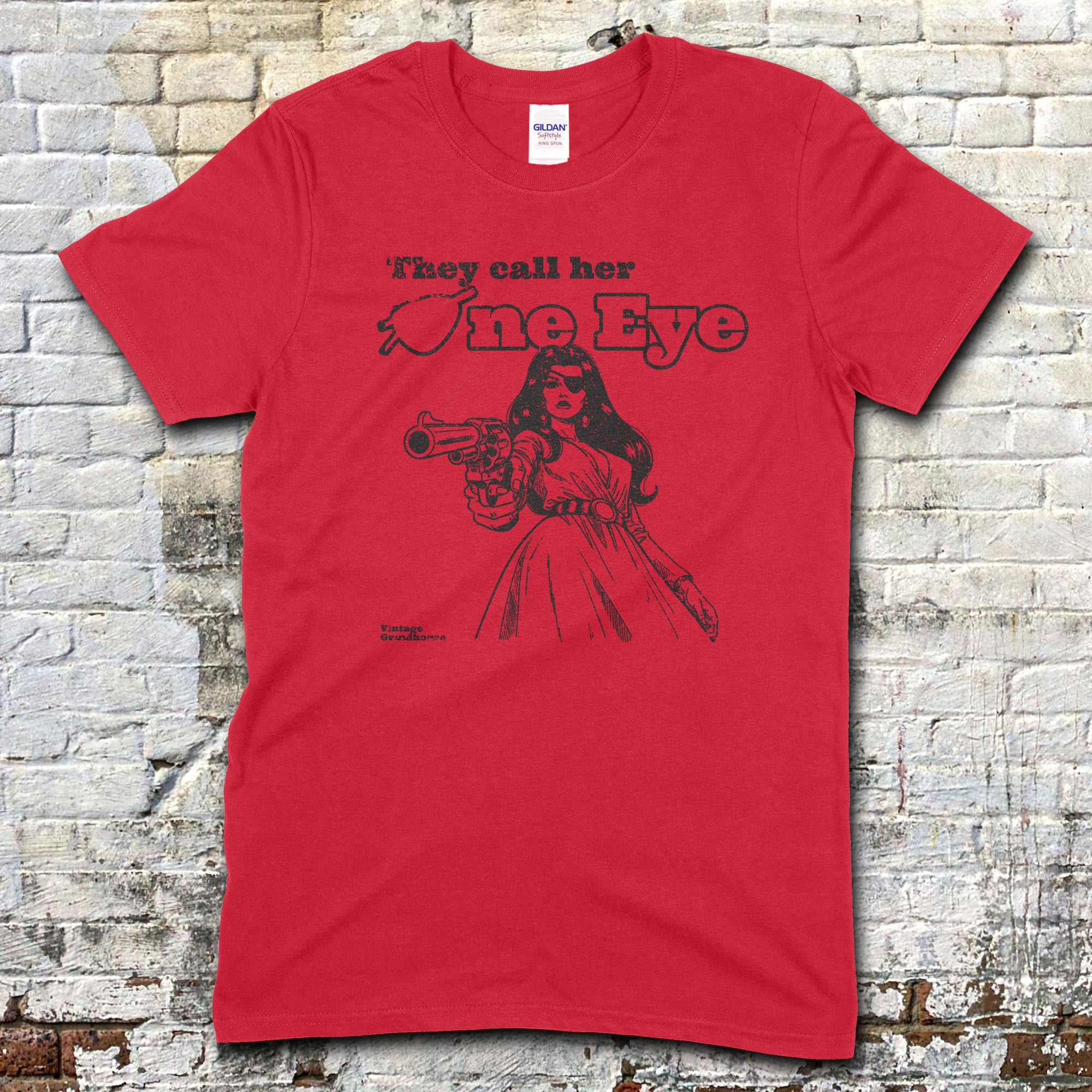 Red t-shirt featuring a black graphic of a woman pointing a gun with They call her One Eye text on front