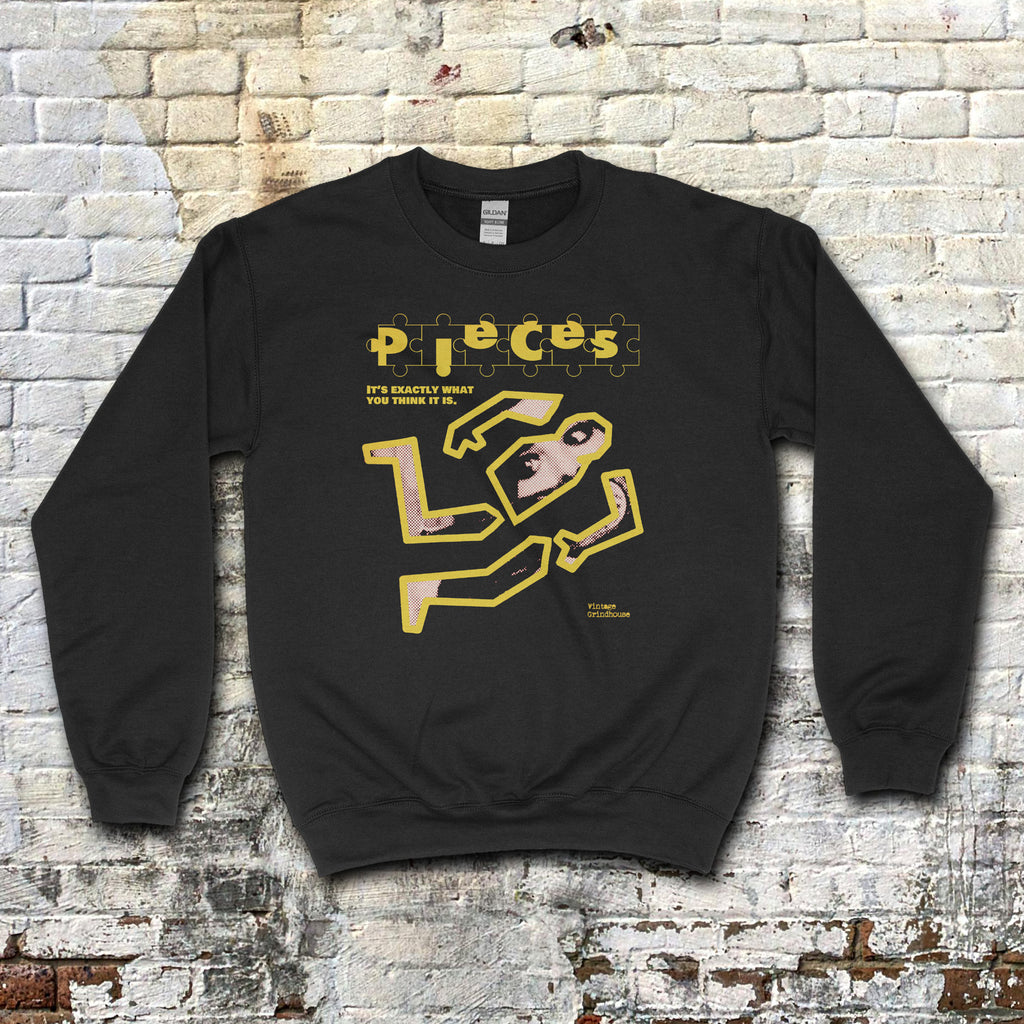 Pieces - Crime Scene Edition sweatshirt with yellow outlined crime scene graphic and stylized text on black fabric against brick wall