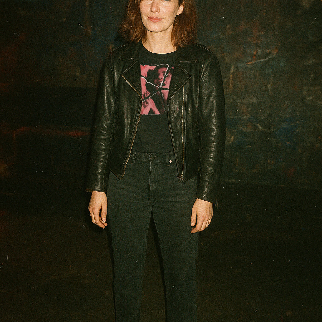 Person wearing Pieces - Torn Asunder Edition t-shirt with abstract pink and black graphic and black leather jacket in dim setting