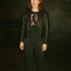 Person wearing Pieces - Torn Asunder Edition t-shirt with abstract pink and black graphic and black leather jacket in dim setting