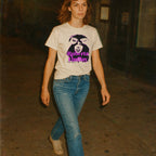 Person wearing a t-shirt with a graphic design of a woman's face and text, walking indoors.