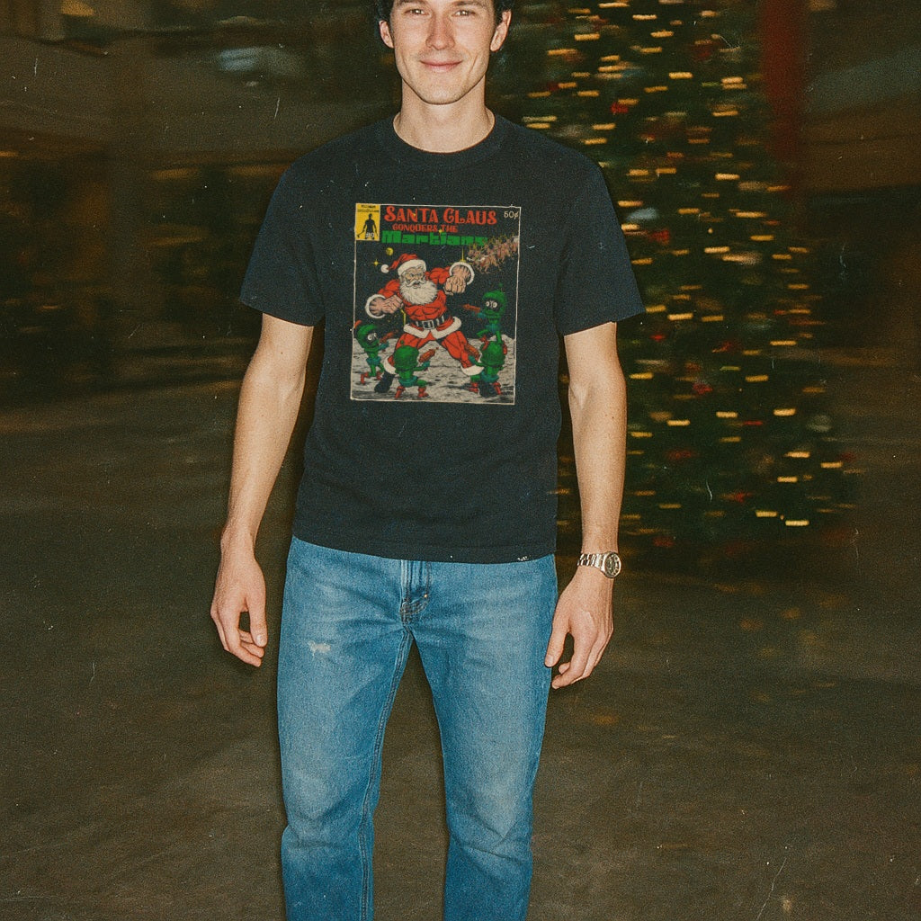 Man wearing Santa Claus Conquers the Martians t-shirt featuring retro comic-style Santa and Martian characters outdoors at night