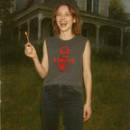 Woman outdoors at dusk smiling and wearing The Burning muscle tank with red graphic design on dark fabric