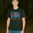 Man wearing a black t-shirt with graphic design in a dark indoor setting