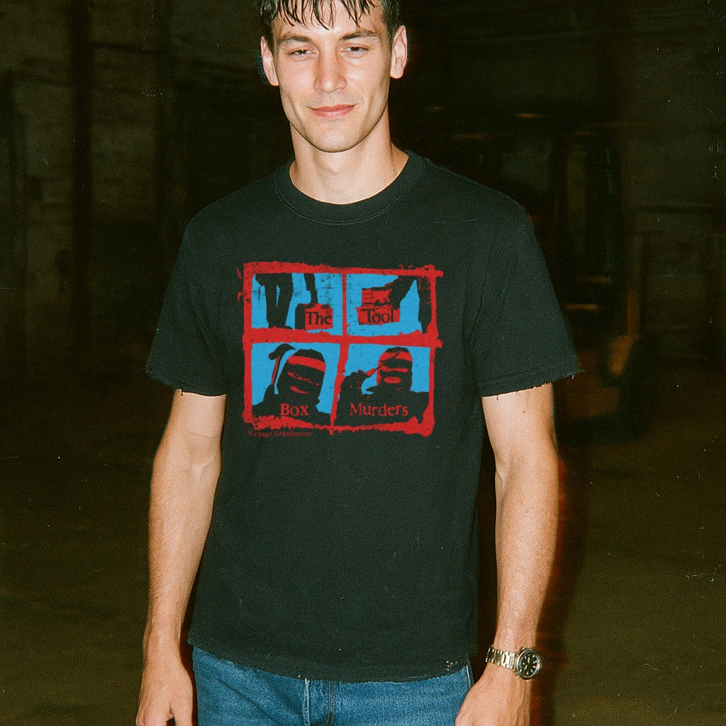 Man wearing a black t-shirt with graphic design in a dark indoor setting