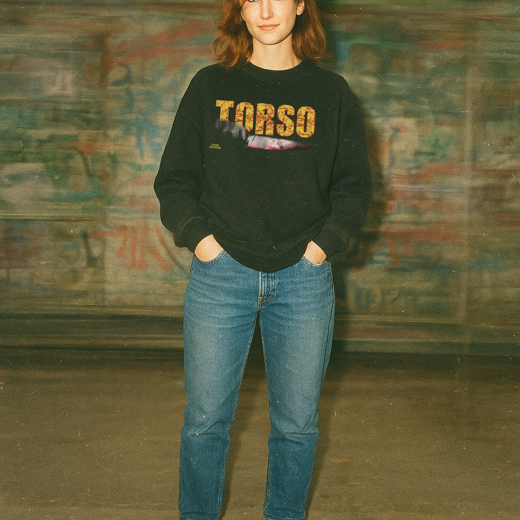 Torso sweatshirt with vintage yellow text and graphic of a pale arm on black fabric worn by person indoors