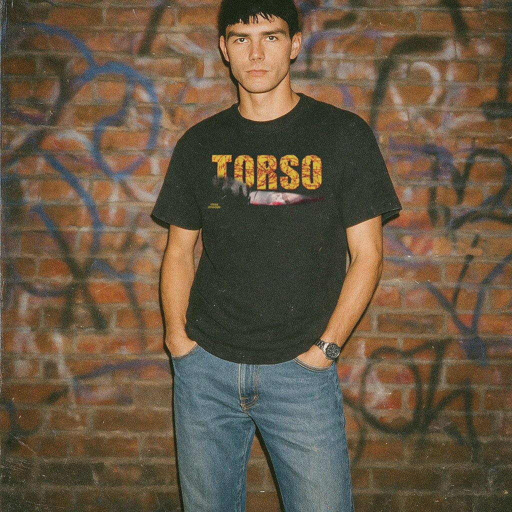Person wearing a black t-shirt with 'TORSO' text in front of a graffiti-covered brick wall.