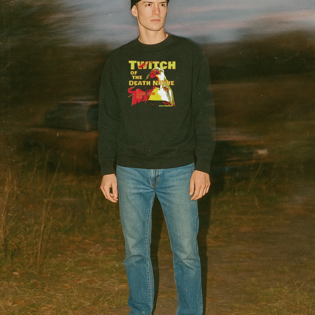 Twitch of the Death Nerve sweatshirt with striking vintage horror print worn outdoors at dusk by standing model