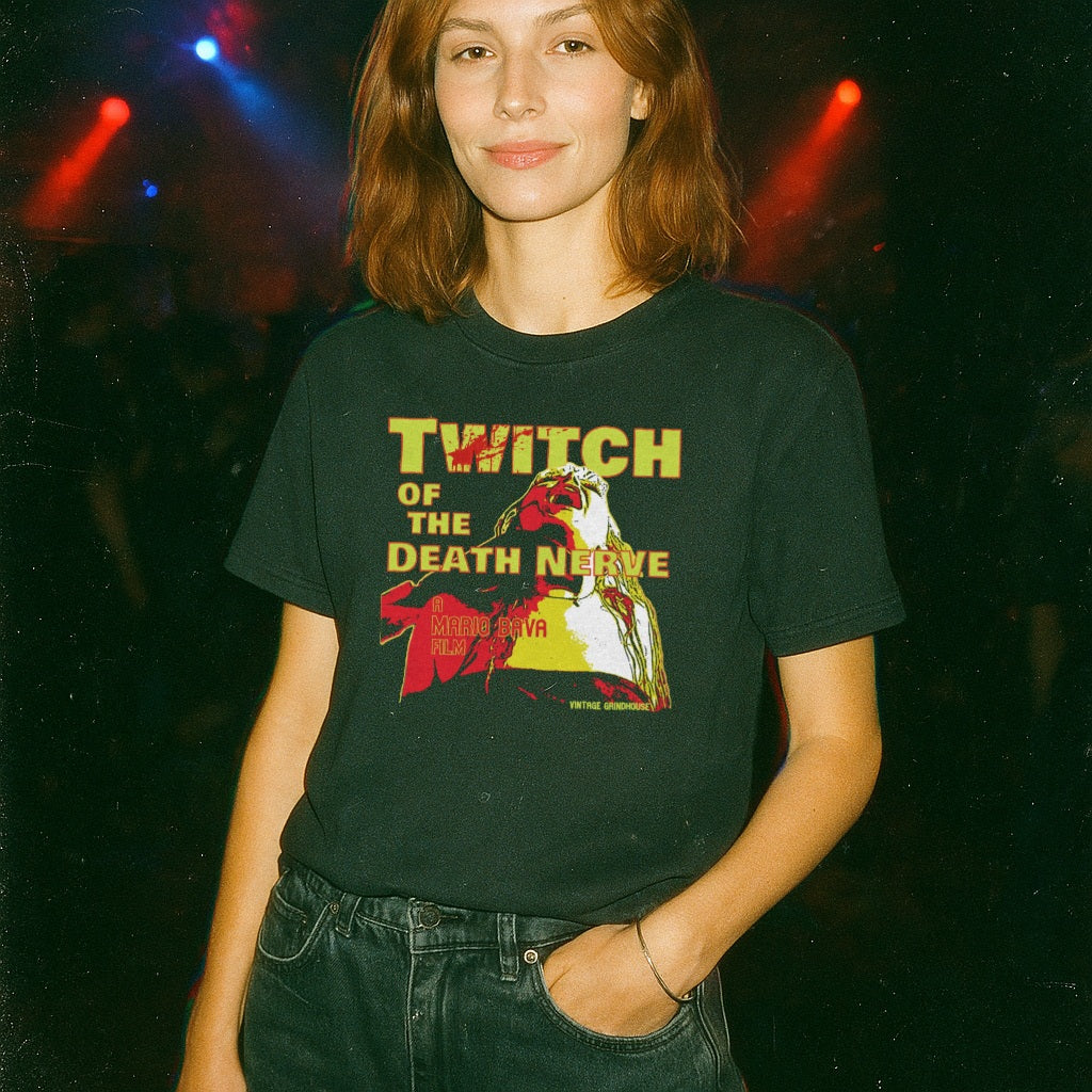 Woman wearing black Twitch of the Death Nerve t-shirt featuring bold yellow and red graphic design at a concert venue
